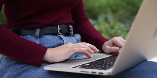女性的手，年轻的商业女性在户外工作与笔记本电脑