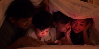 亚洲家庭的视频系列，快乐的爸爸妈妈和女儿在家看电影在卧室。