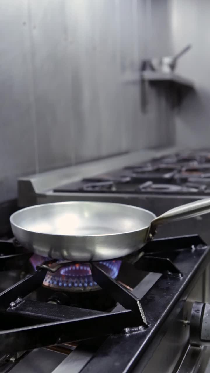 厨师用平底锅煮蛤蜊和大蒜。垂直视频。特写镜头。
