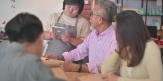 亚洲女性患有唐氏综合症的女服务员在咖啡馆使用数字平板电脑为顾客点菜