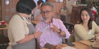 亚洲女性患有唐氏综合症的女服务员在咖啡馆使用数字平板电脑为顾客点菜