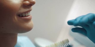 一位男性牙医用牙齿美白台为微笑的病人选择牙齿的颜色。牙科治疗和护理。口腔卫生。医疗保健理念。