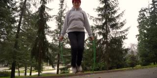 年长的女运动员在公园里跳绳
