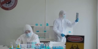 科学家在防护服和防护面罩使用平板电脑视频会议。
