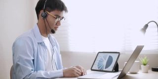 亚洲商人戴上耳机在笔记本电脑上进行视频会议