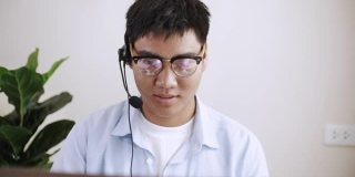 亚洲商人戴上耳机在笔记本电脑上进行视频会议