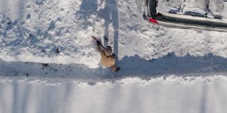 一名成年男子在一场冬季降雪后用铲子清理车道上的积雪。鸟瞰无人机正上方的慢动作视频。