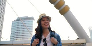 一个美丽的年轻亚洲女人在首都旅行的乐趣。看着交通高峰时段的交通和空中列车的背景。