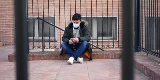 一个戴着面具的年轻人坐在路边听音乐