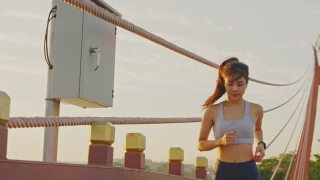 亚洲年轻美丽的女人在傍晚的夕阳在大桥在公共公园跑步健康。运动员健康和坚定的女孩锻炼通过慢跑锻炼户外运动为她的健康。视频素材模板下载