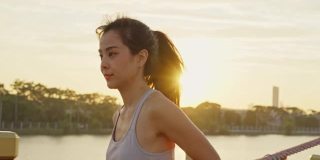 亚洲年轻美丽的女人在傍晚的夕阳在大桥在公共公园跑步健康。运动员健康和坚定的女孩锻炼通过慢跑锻炼户外运动为她的健康。