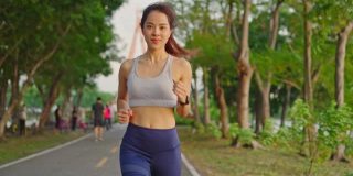 亚洲年轻美丽的女人为健康在傍晚日落在街道上的公园。运动员健康和坚定的女孩锻炼通过慢跑锻炼户外运动为她的健康。