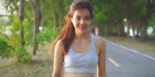 肖像快乐的亚洲年轻美丽的女人站在傍晚日落在大街上的公园。健身健硕的运动员在户外进行慢跑健身运动，以保持身体健康。