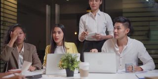 亚洲青年商务人士小组在办公室举行讨论会议。男人和女人有头脑风暴和团队合作加班。公司的现代同事工作到深夜。