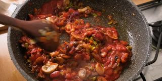 慢动作搅拌和烹饪意大利扁面，配上番茄酱、橄榄和蘑菇