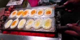 蛋饼是一种美味的街头食品制作过程，晚上在街上的商店用火加热。