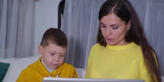 远程课程，照顾她心爱的男孩的女性父母通过笔记本电脑上的视频通信使用现代技术，而休闲度假在拖车