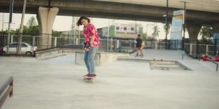 一群亚洲青少年在混凝土地板上玩滑板。