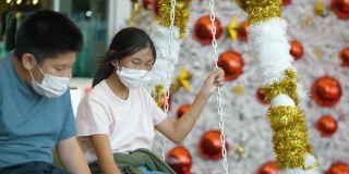 快乐的亚洲儿童戴着面具和拍照或自拍与圣诞树的背景，假日概念。