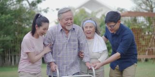 一位生病的老人正在用助行器学习在花园里散步。亚洲家庭共同生活在幸福的花园，健康保健的保险理念
