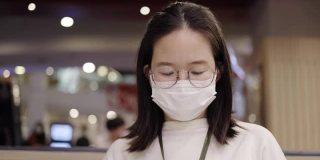 亚洲商界女性戴口罩预防冠状病毒感染。使用智能手机了解COVID-19疫情。在社区或餐厅保持社交距离。医疗保健新常态