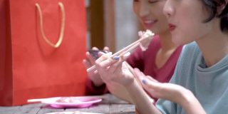 亚洲幸福女人吃饺子和玩手机在户外桌子café。概念时尚女孩的生活方式。