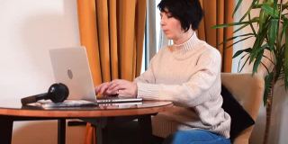 一名孕妇坐在桌子前，面前是一台笔记本电脑。离开了桌子。