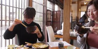 年轻女性在日本餐馆吃“Donabe Gohan”健康的日本食物