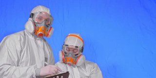 科学家病毒学家在呼吸器上用手写笔在平板电脑上写字。一男一女戴着医用防护口罩。色度键蓝色。