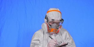 科学家病毒学家在呼吸器上用手写笔在平板电脑上写字。戴医用防护口罩的妇女。色度键蓝色。