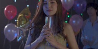 一个亚洲年轻女子在晚会上喝酒和大笑的4k视频。妇女们在圣诞节和新年互相庆祝。