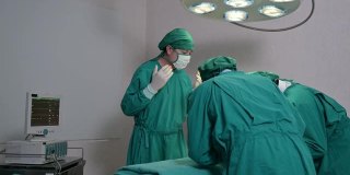 亚洲外科医生和助手在手术室里捡起手术设备为一名严重受伤的病人做手术