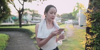 年轻活跃的亚洲女性在以日落为背景的公园里与朋友视频通话，分享健康的生活方式故事，人类现代科技，适应新的正常距离