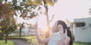 年轻的亚洲女性朋友用手机视频通话在公园锻炼，享受户外公园锻炼，健康的生活体验，拥有在线数字通信，无线技术