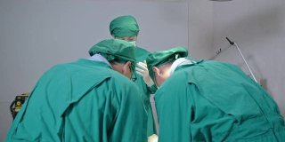 在医院的手术室里，外科医生们穿着手术服给一名严重受伤的病人做手术