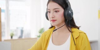 亚洲商界女性在新常态下保持社交距离以预防病毒，同时在办公室使用笔记本电脑向同事演示视频通话计划。