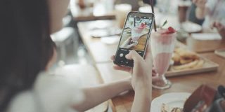 一个女人在咖啡店用智能手机拍照