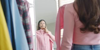 美丽迷人的亚洲女士在衣柜上挑选衣服，在家卧室里照镜子梳妆。