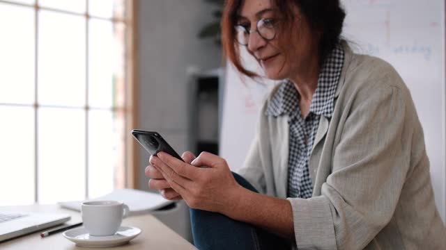 一位英语老师在家里为她的学生开设了在线课程。她休息一会儿喝咖啡。在此期间，他还使用自己的智能手机