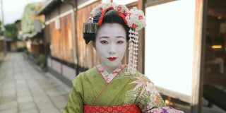 舞妓(正在训练的艺妓)站在京都祗园狭窄的小路上