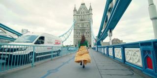 一个漂亮的女孩穿着裙子在伦敦塔桥上奔跑，英国。