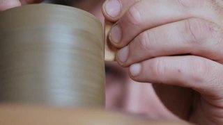 特写镜头。陶工在陶工轮上加工一个陶土茶壶的边缘。陶瓷艺术的概念。手工制作的陶器。陶工制作粘土制品视频素材模板下载
