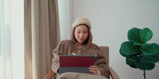 在家工作时使用平板电脑和触控笔的时髦女性。