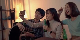 年轻的亚洲朋友在私人聚会上用智能手机自拍。