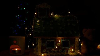 用软熊装饰自制的甜饼屋，在香薰灯中点缀发光的蜡烛，散光的节日花环装饰模糊了圣诞树的散光灯的黑暗背景。新年前夜4K视频视频素材模板下载