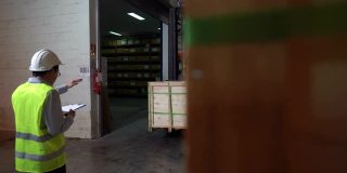 两名亚洲男性仓库工人在零售仓库一起使用叉车搬运纸箱