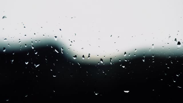 小雨的背景，雨点落在玻璃上，雨点滴在窗户上，窗外闪电，雷雨，雨水倾泻。