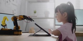 女孩在数字平板电脑上控制机器人手臂，在高中上机器人课