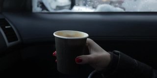 女人在冬天坐在车里喝着热饮