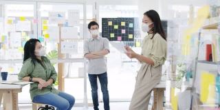 亚洲商务人士在新常态的办公室里开会，头脑风暴，进行商业演示，想法，项目同事，并戴上防护口罩。